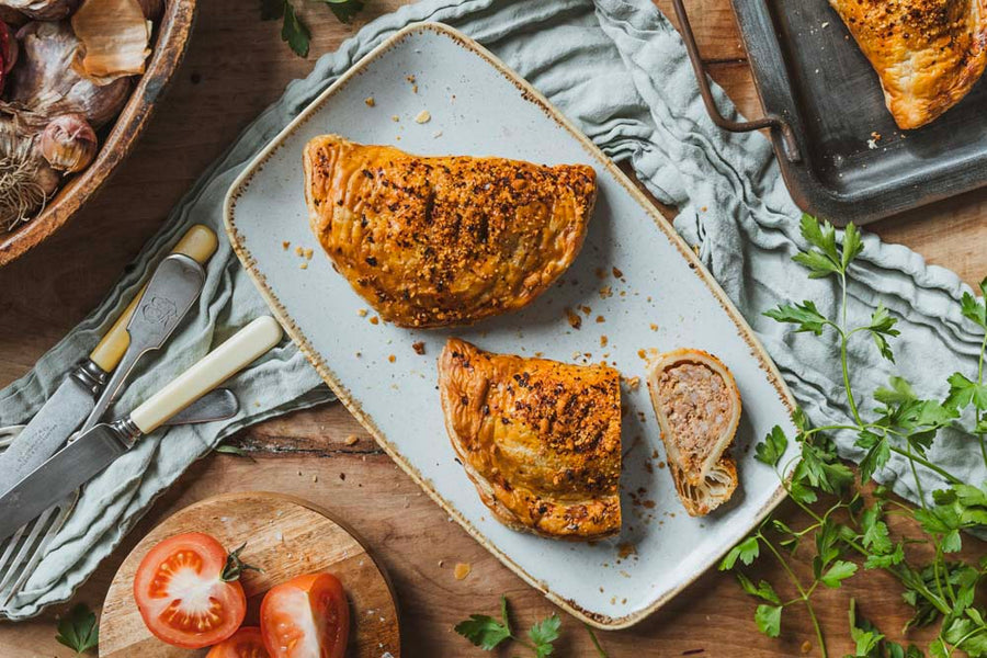 Two BBQ Pulled Pork Pasties, one is cut showing the pulled pork filling