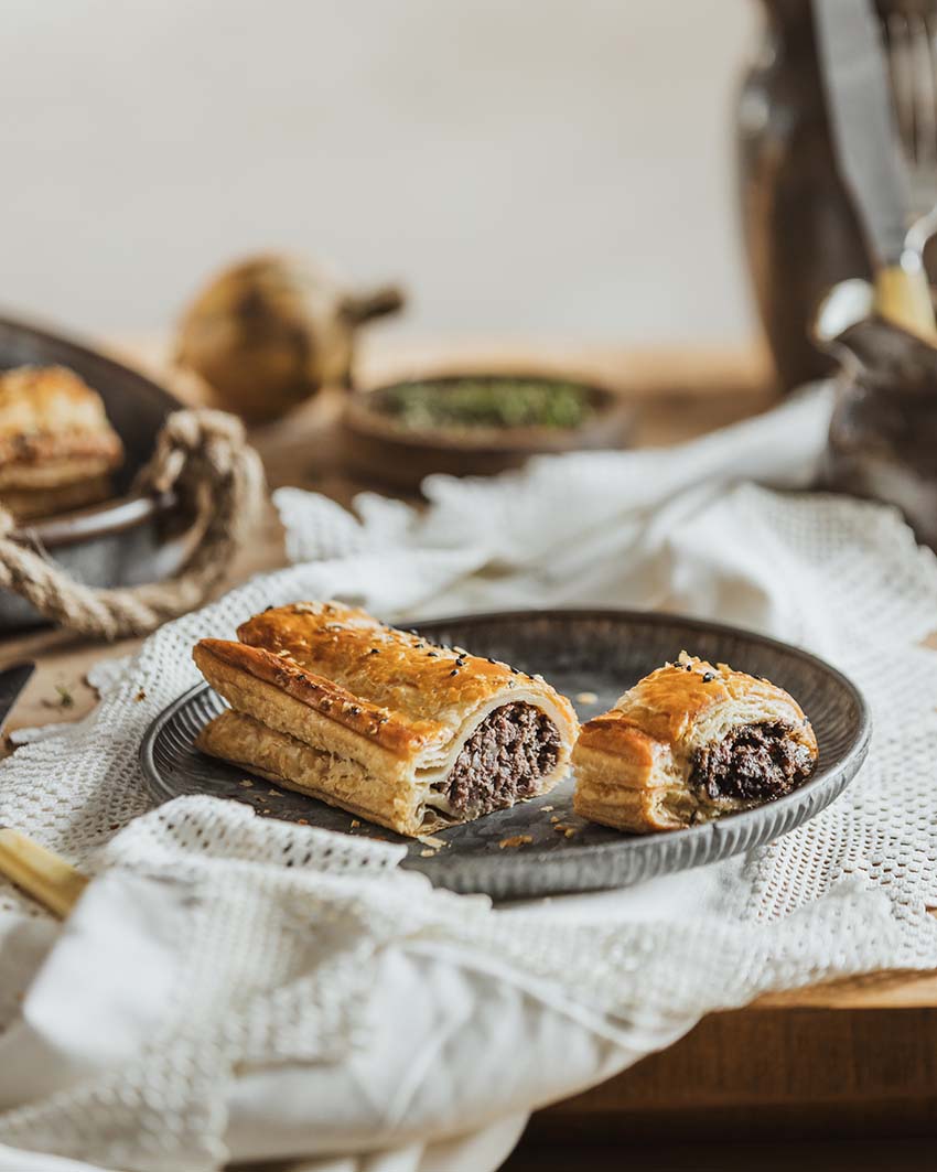 Pork, Black Pudding & Apple Sausage Roll cut open showing the filling on a stylish plate